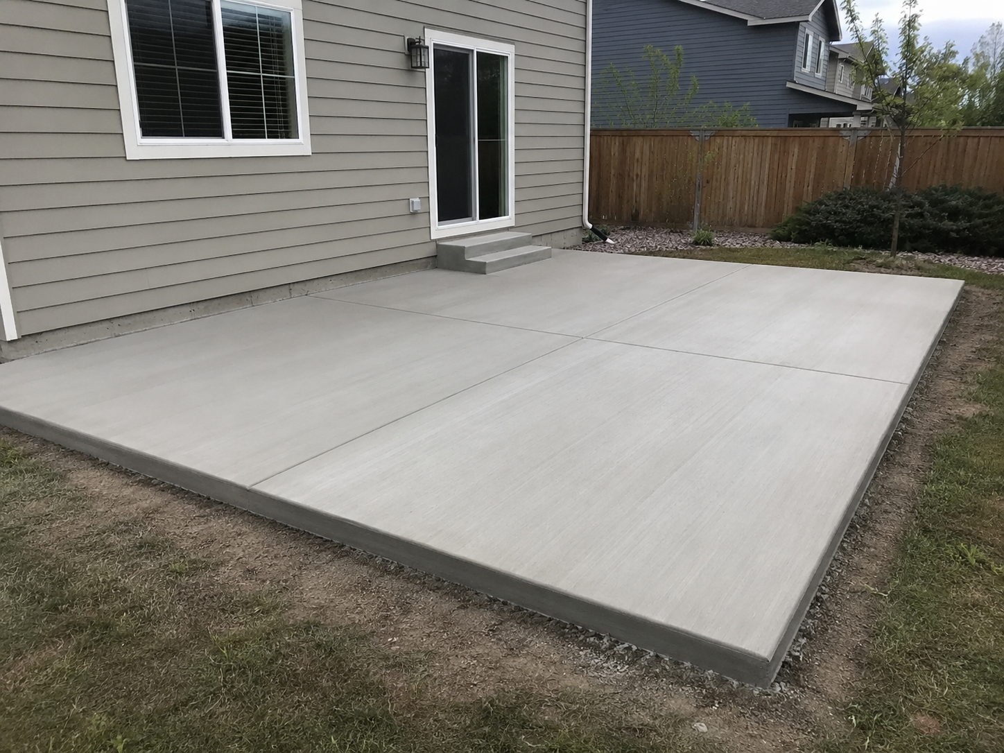 Large clean concrete patio pad behind a residential home